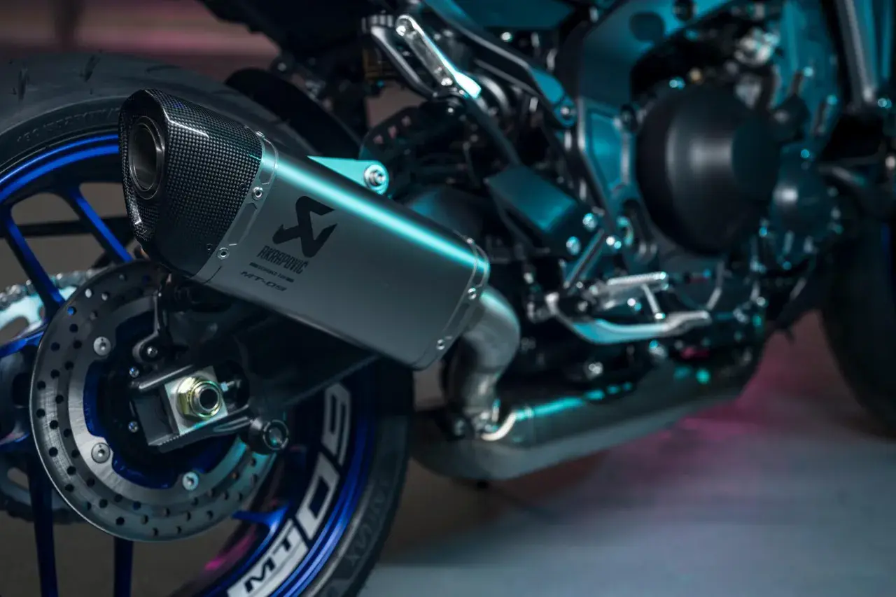 Wydech Akrapovič na motocyklu Yamaha MT-09, z karbonową końcówką i niebieskimi detalami felgi.