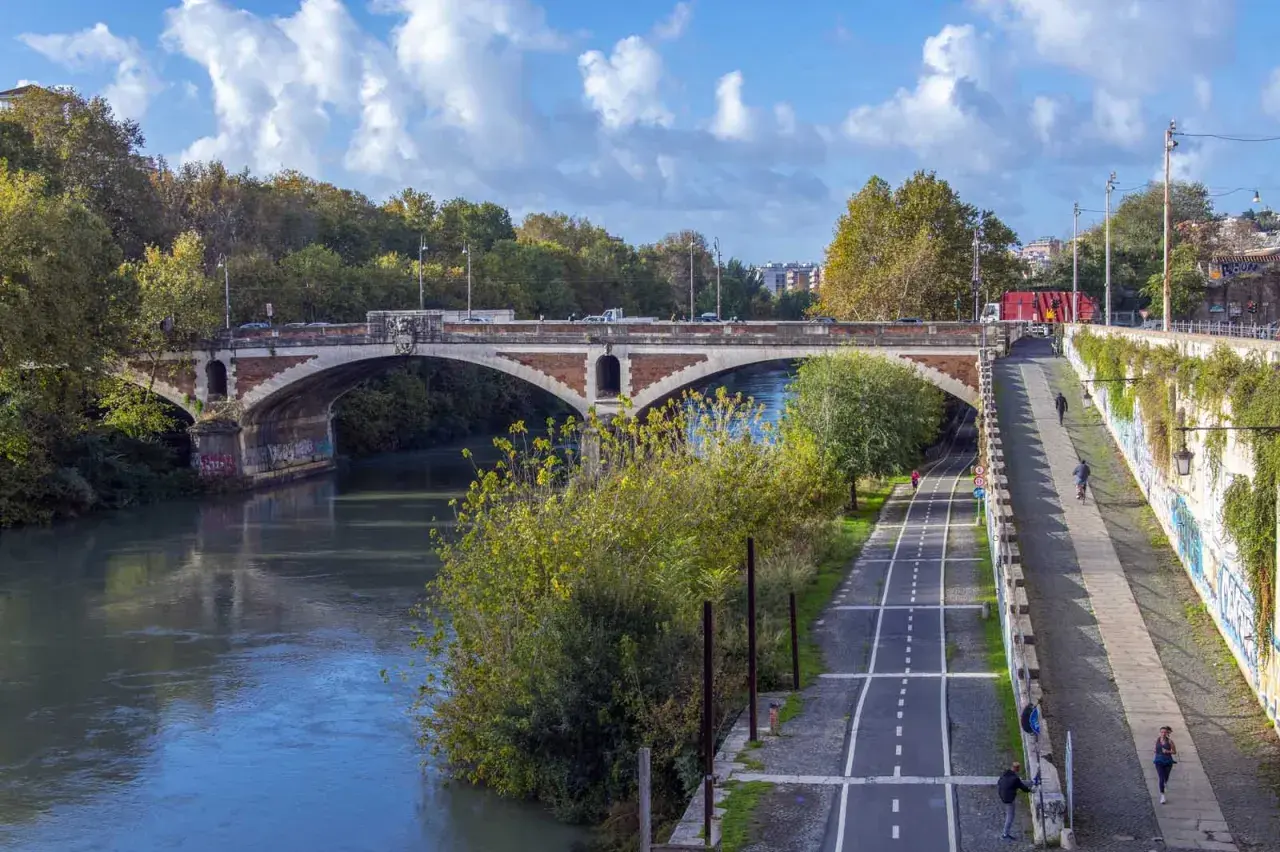 Il ponte nuovo di Roma attraversa il Tevere, con una pista ciclabile e pedonale lungo la riva.