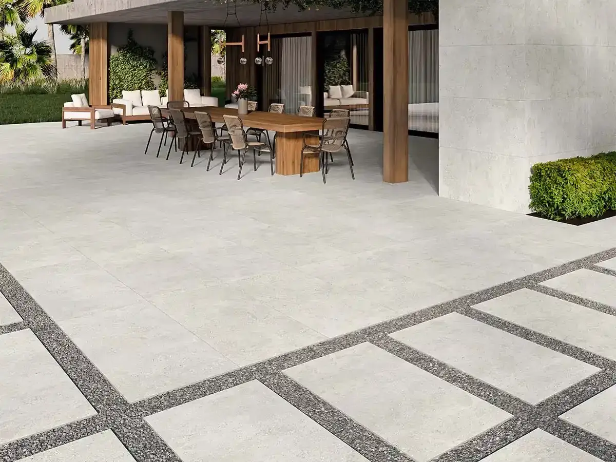 Terraza moderna con suelo de porcelánico que es resistente y elegante, rodeada de vegetación y mobiliario exterior.