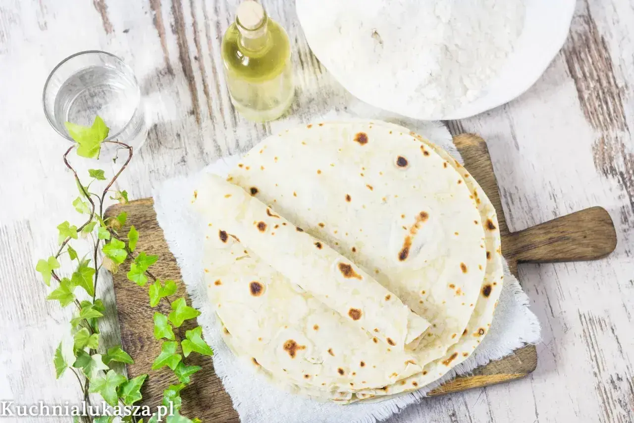 Domowy tortilla przepis: świeżo upieczone placki, mąka, olej i woda na drewnianej desce.