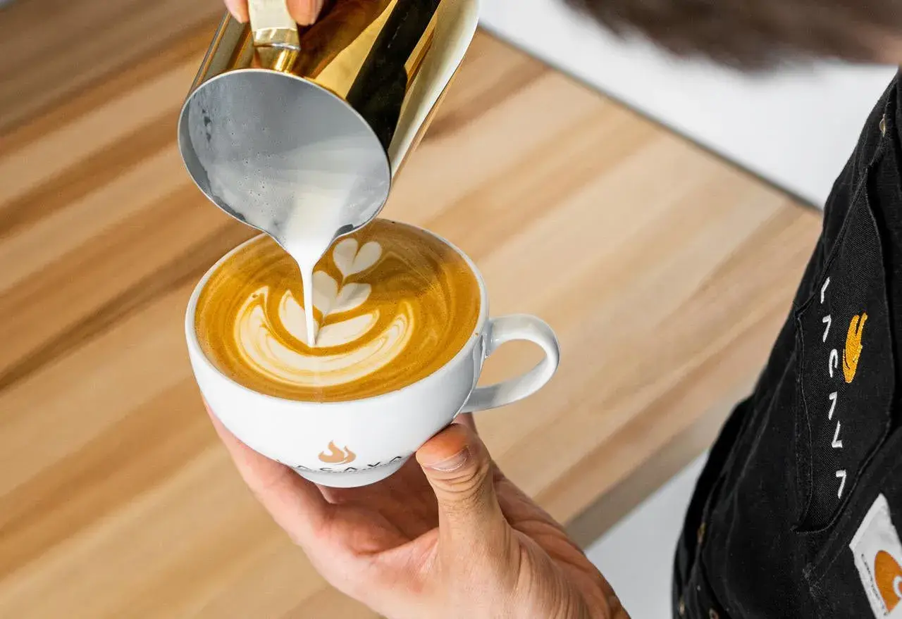 Barista tworzy latte art, wlewając spienione mleko do kawy. To świetny pomysł na to, co zamiast mleka do kawy, gdy szukasz czegoś innego.