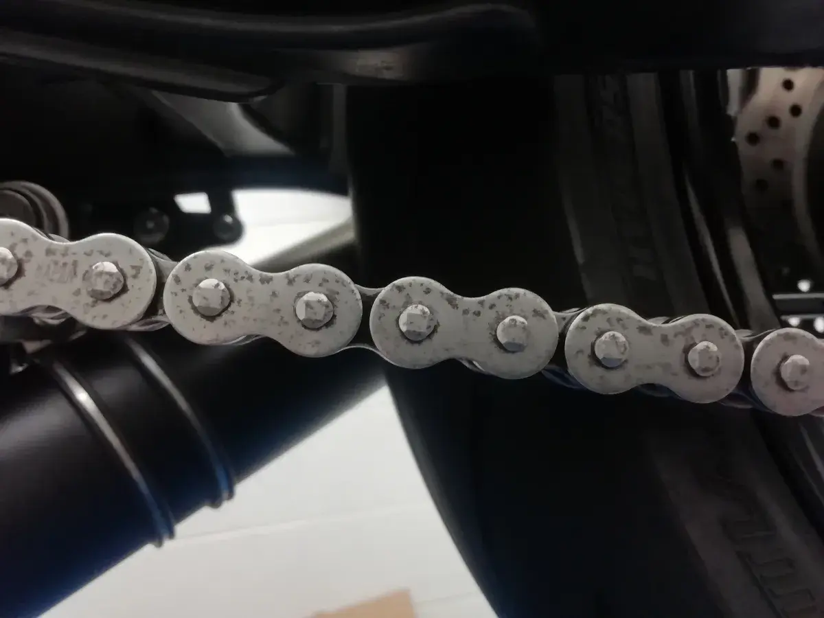 La catena di una moto mostra segni di ruggine, indicando la necessità di manutenzione.