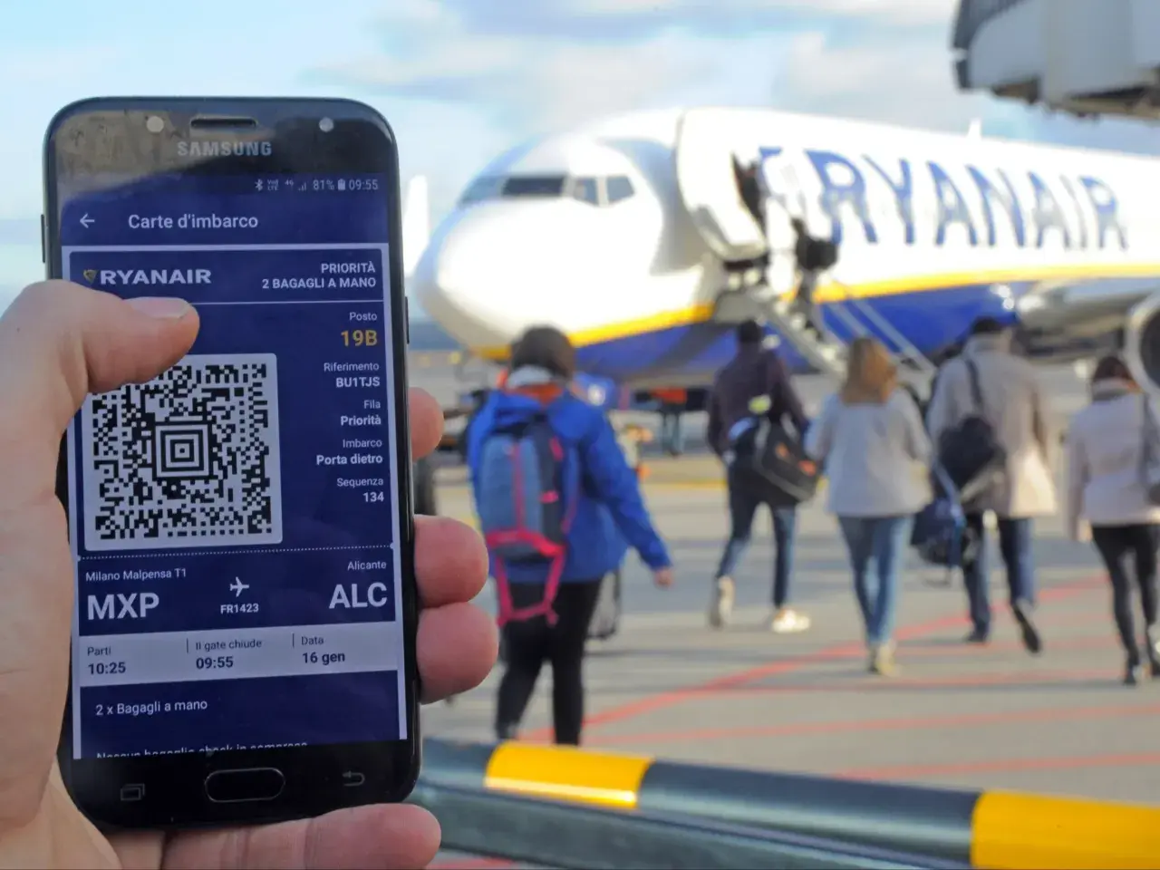 Telefon z kartą pokładową Ryanair, gotowy do podróży. W tle samolot i pasażerowie.