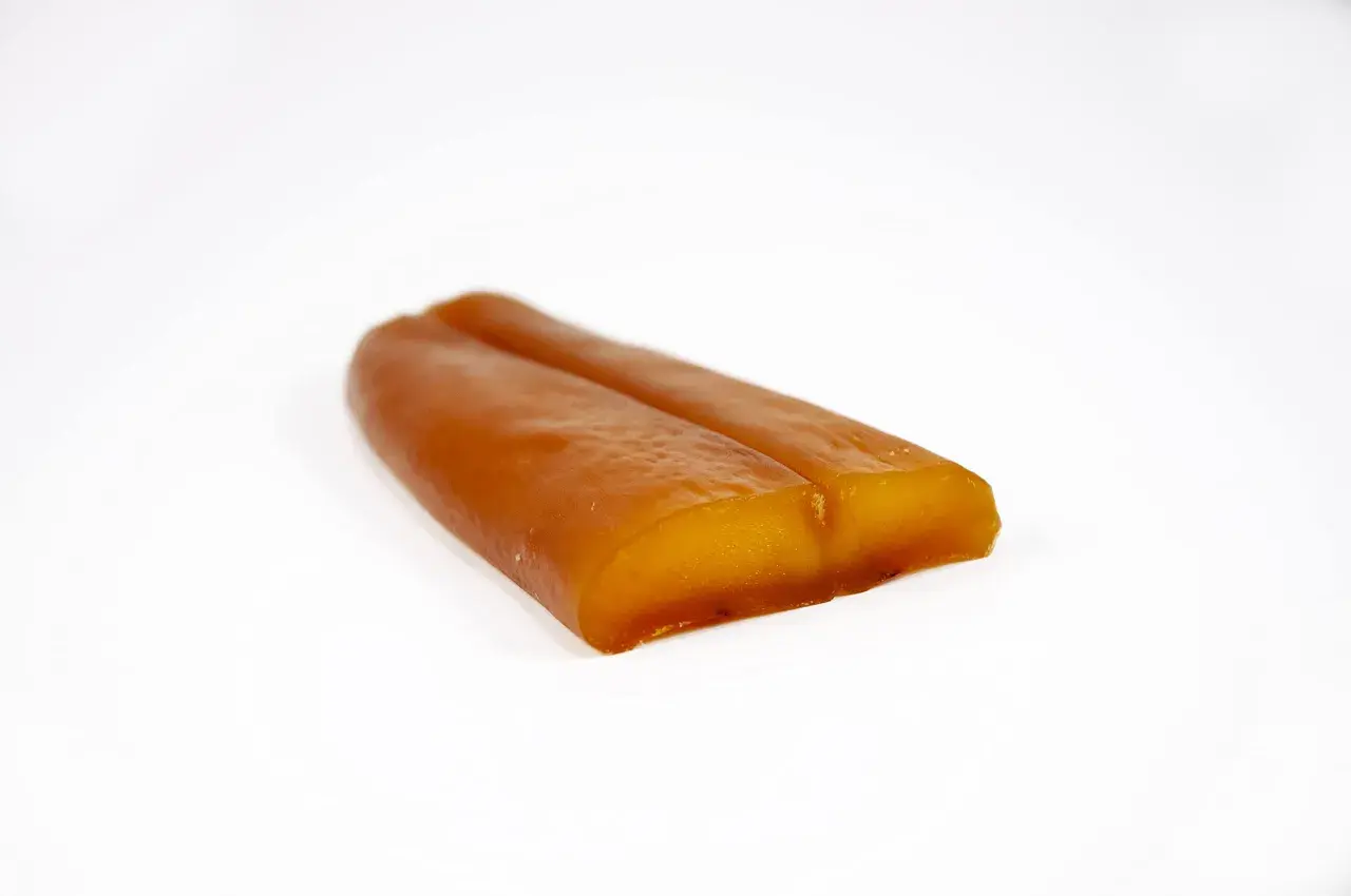 Zwei goldbraune, längliche Stücke Bottarga di Muggine liegen nebeneinander auf weißem Grund.
