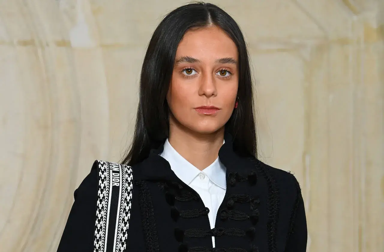 Joven con estilo cayetano, luce un blazer oscuro con detalles de pasamanería y una camisa blanca. Su bolso Dior complementa el look.