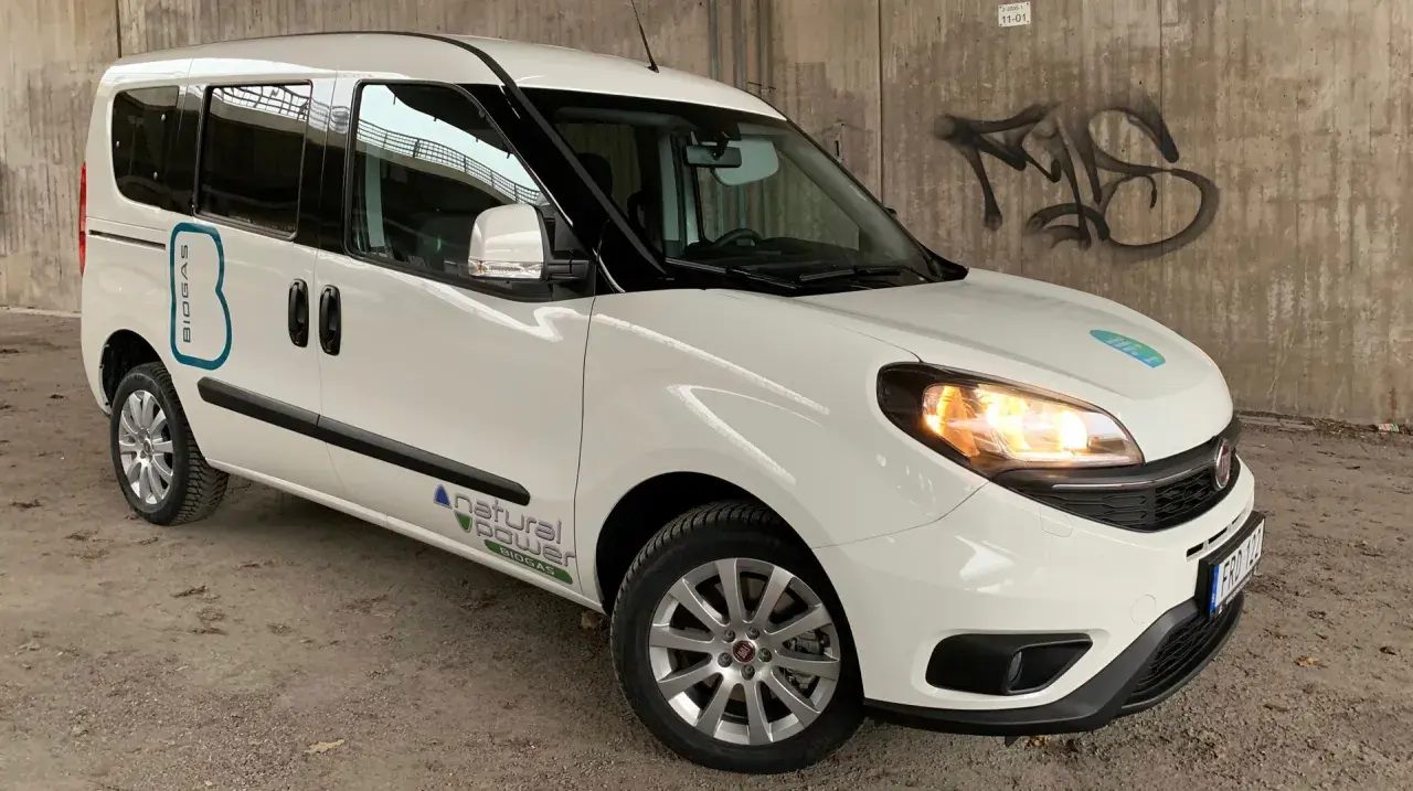 Vit Fiat Doblo med texten "BIOGAS" och "natural power" på sidan. En bil med ett potentiellt fiat doblo problem, kanske relaterat till dess biogasdrift.