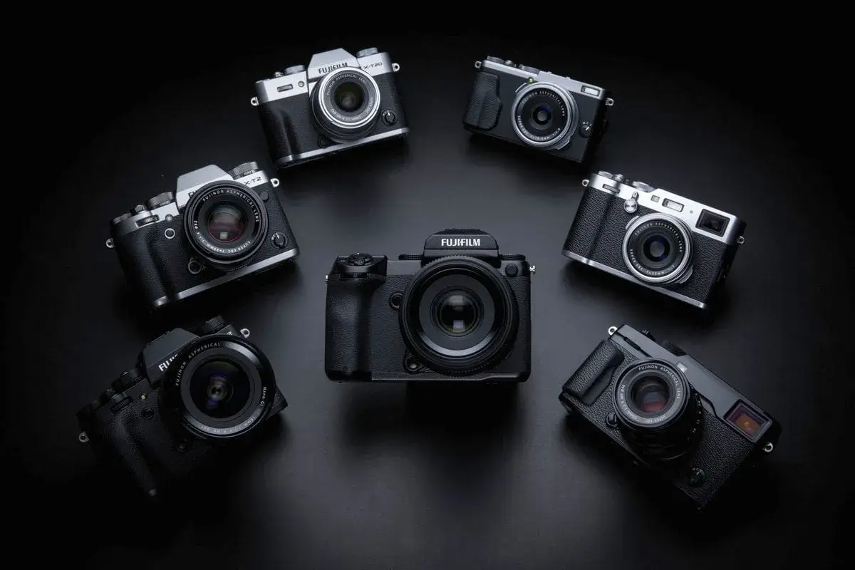 Kolekcja aparatów Fujifilm ułożona w okrąg. W centrum duży, czarny korpus, a wokół niego mniejsze modele, w tym X-T20. Każdy aparat to potencjalna pełna klatka możliwości.