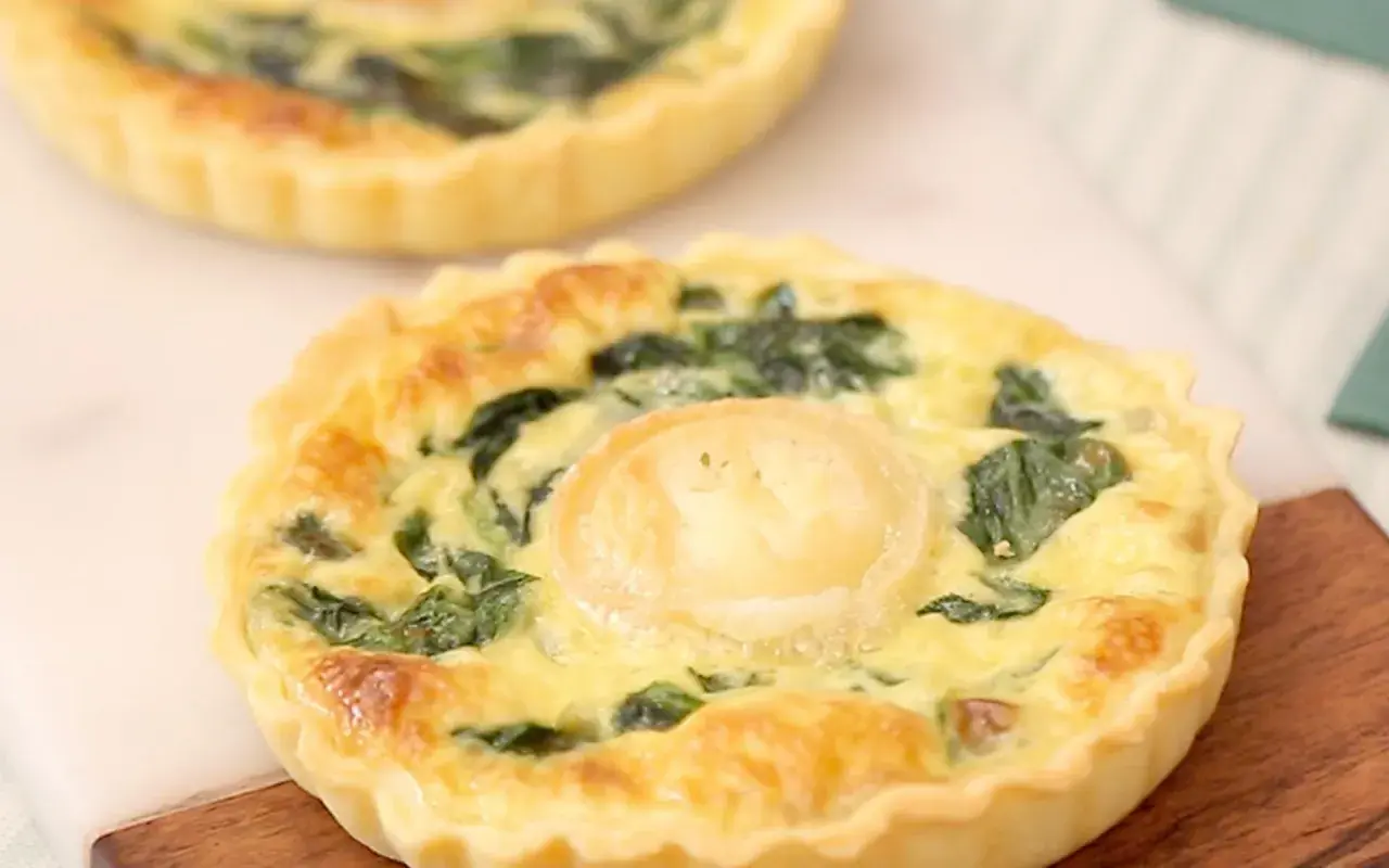 Une délicieuse quiche épinard chèvre, dorée et appétissante, avec une touche de fromage de chèvre au centre.