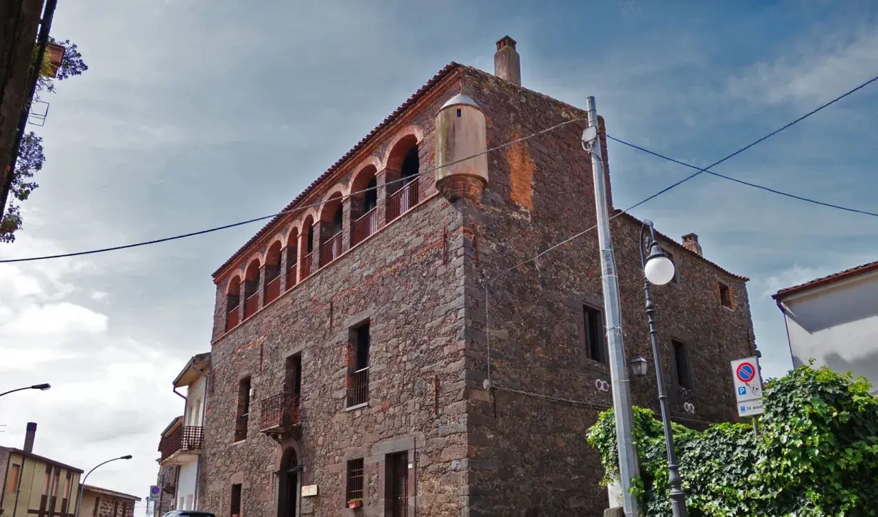Stone building with arched balconies and a turret against a cloudy sky.