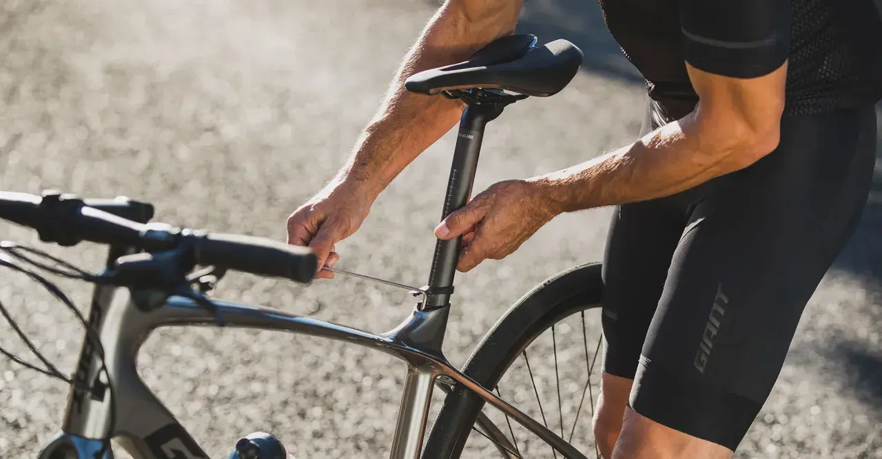 Rowerzysta reguluje wysokość siodełka, by uzyskać optymalną pozycję na rowerze szosowym.