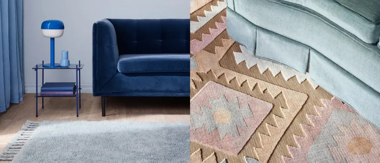 A dark blue sofa next to a light blue rug and a patterned rug with geometric designs.