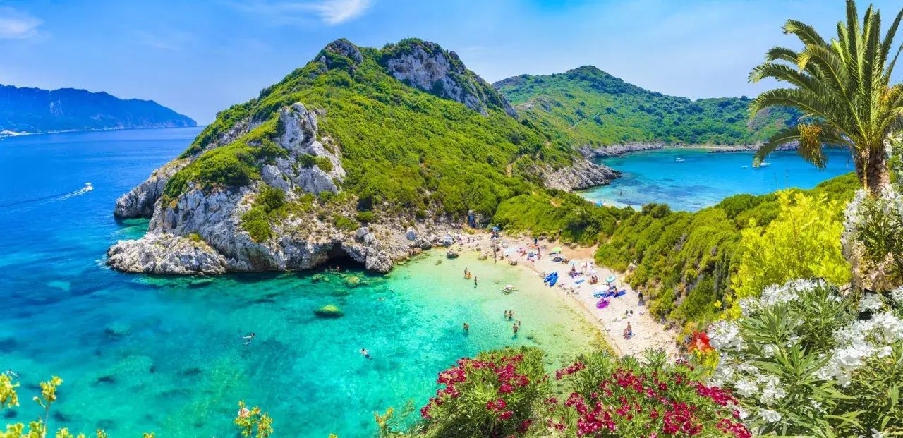 Malownicza zatoka z turkusową wodą i piaszczystą plażą. W maju Grecja zachwyca zielenią i kwitnącymi kwiatami.