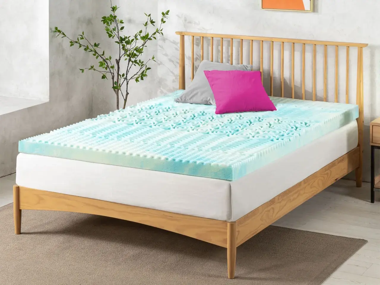 A blue and white memory foam mattress topper with a textured surface sits on a wooden bed frame. Perhaps this is why is my memory foam mattress so uncomfortable.