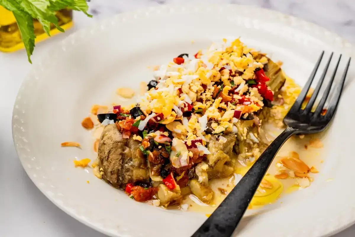 Deliciosa ensalada de berenjenas asadas con huevo picado, aceitunas negras, pimientos y almendras.