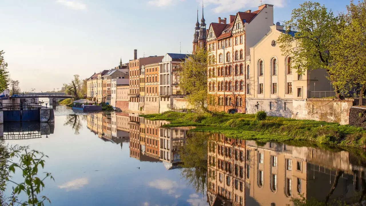 Nad Odrą w Opolu, zabytkowe kamienice odbijają się w spokojnej wodzie. To piękne opole atrakcje, które warto zobaczyć.