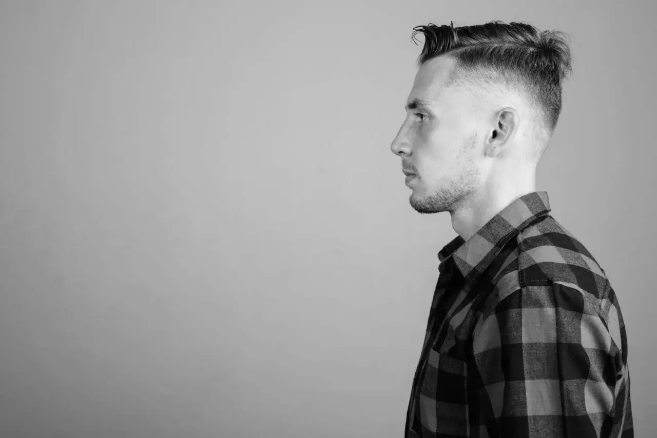 Perfil de hombre con un corte de pelo taper fade moderno y camisa a cuadros.