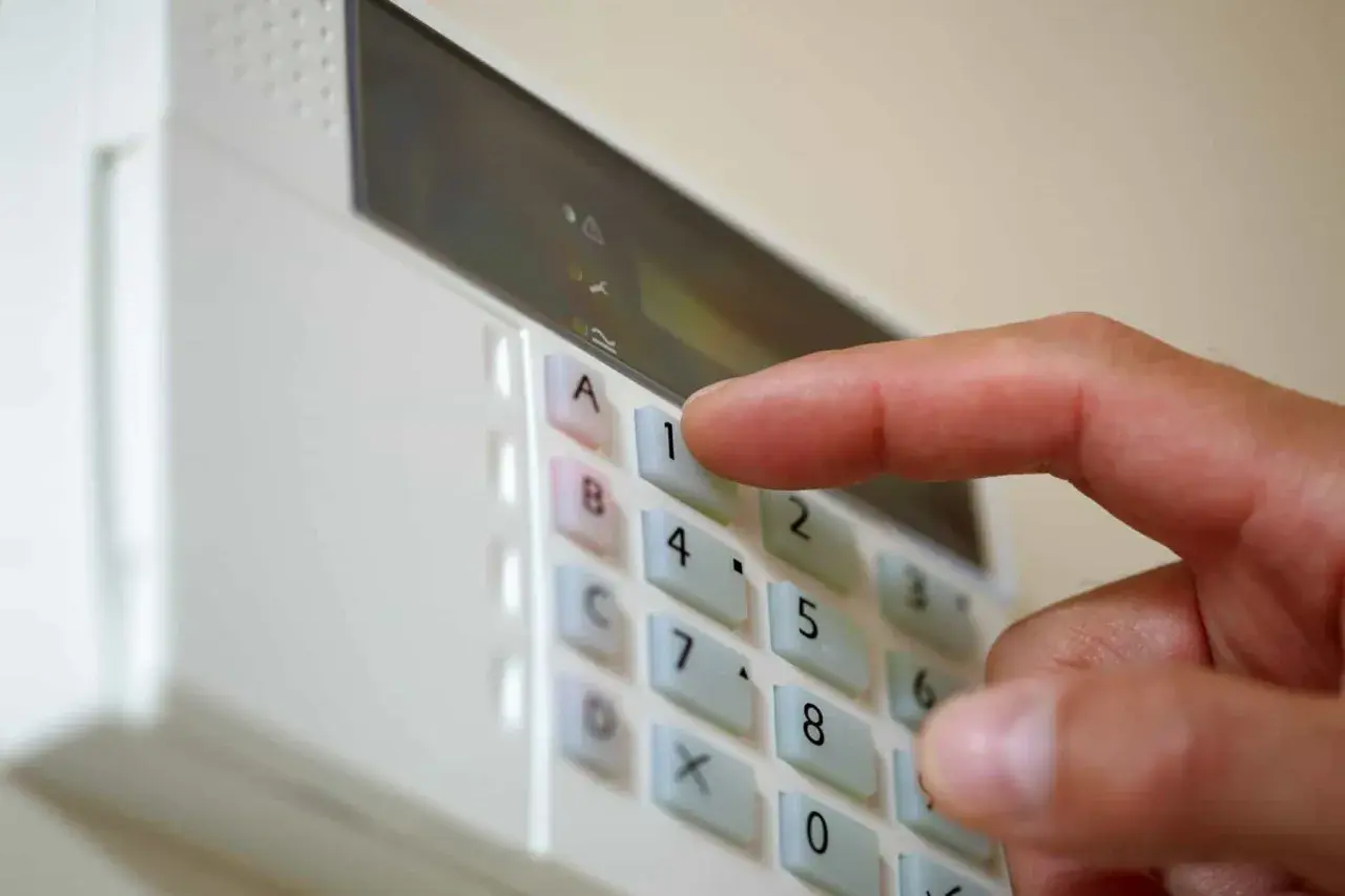 Dłoń naciska klawisz "1" na klawiaturze alarmu domowego.