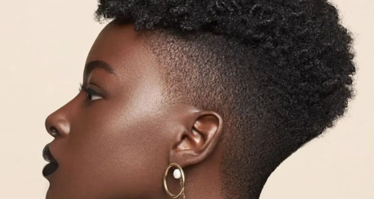 Perfil de mujer con cabello rizado y un moderno taper fade bajo.