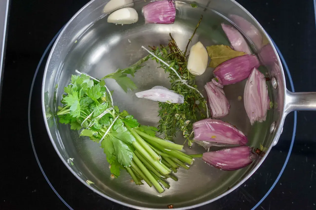 Préparation d'un court-bouillon avec oignons, ail, thym, persil et laurier. Idéal pour le temps de cuisson seiche au court-bouillon.