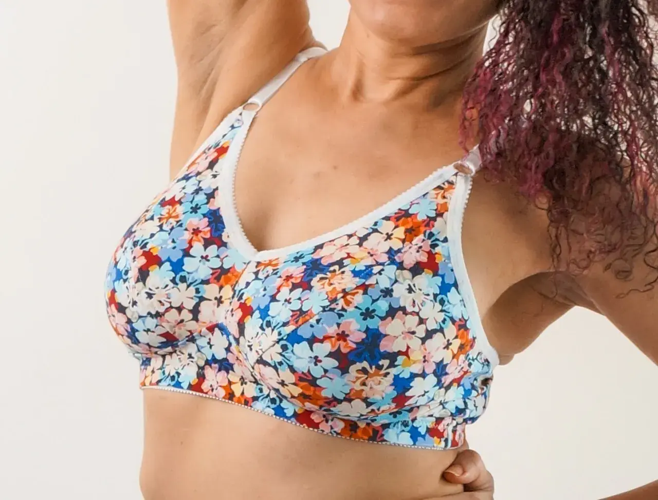 A woman wears a colorful floral bra. This bra pattern is free to download and create your own!