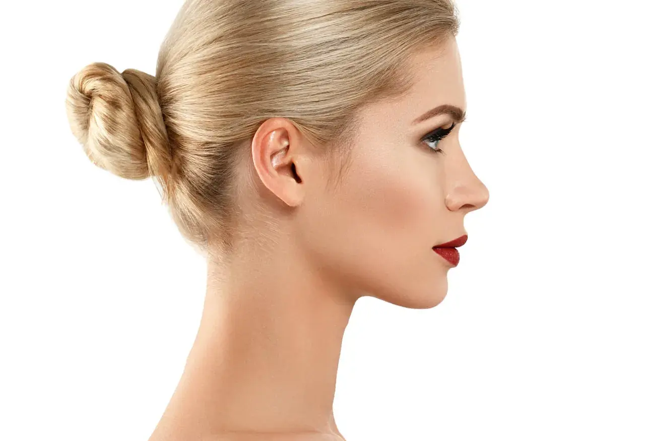Profil kobiety z blond kokiem i subtelnym garbatym nosem, podkreślonym czerwonymi ustami.