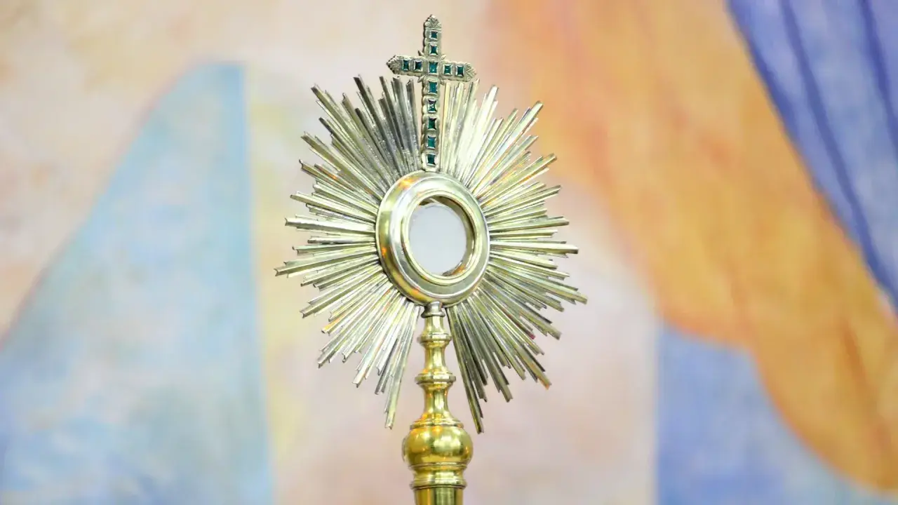 Monstrancja z hostią, symbol cudu w Lanciano, lśni na tle barwnych draperii.