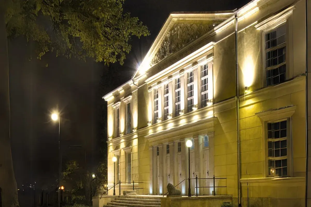 Elegancki budynek teatru w Jeleniej Górze nocą, oświetlony ciepłym światłem.