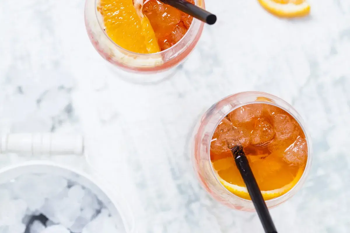 Dwa orzeźwiające drinki Aperol Spritz z plasterkiem pomarańczy i lodem. Idealne na letnie popołudnie.