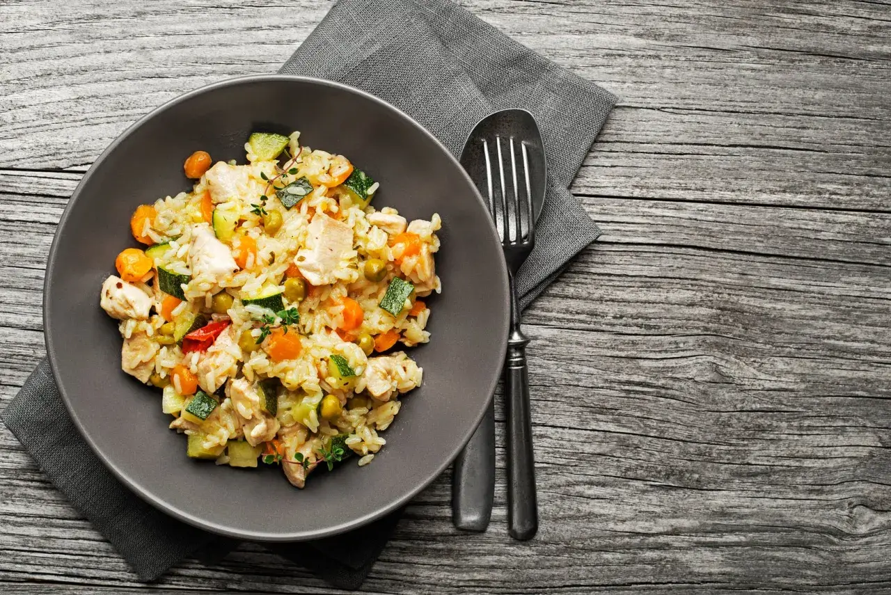 Piatto di riso con pollo e verdure miste, un esempio di alimentazione funzionale per un pasto completo e nutriente.