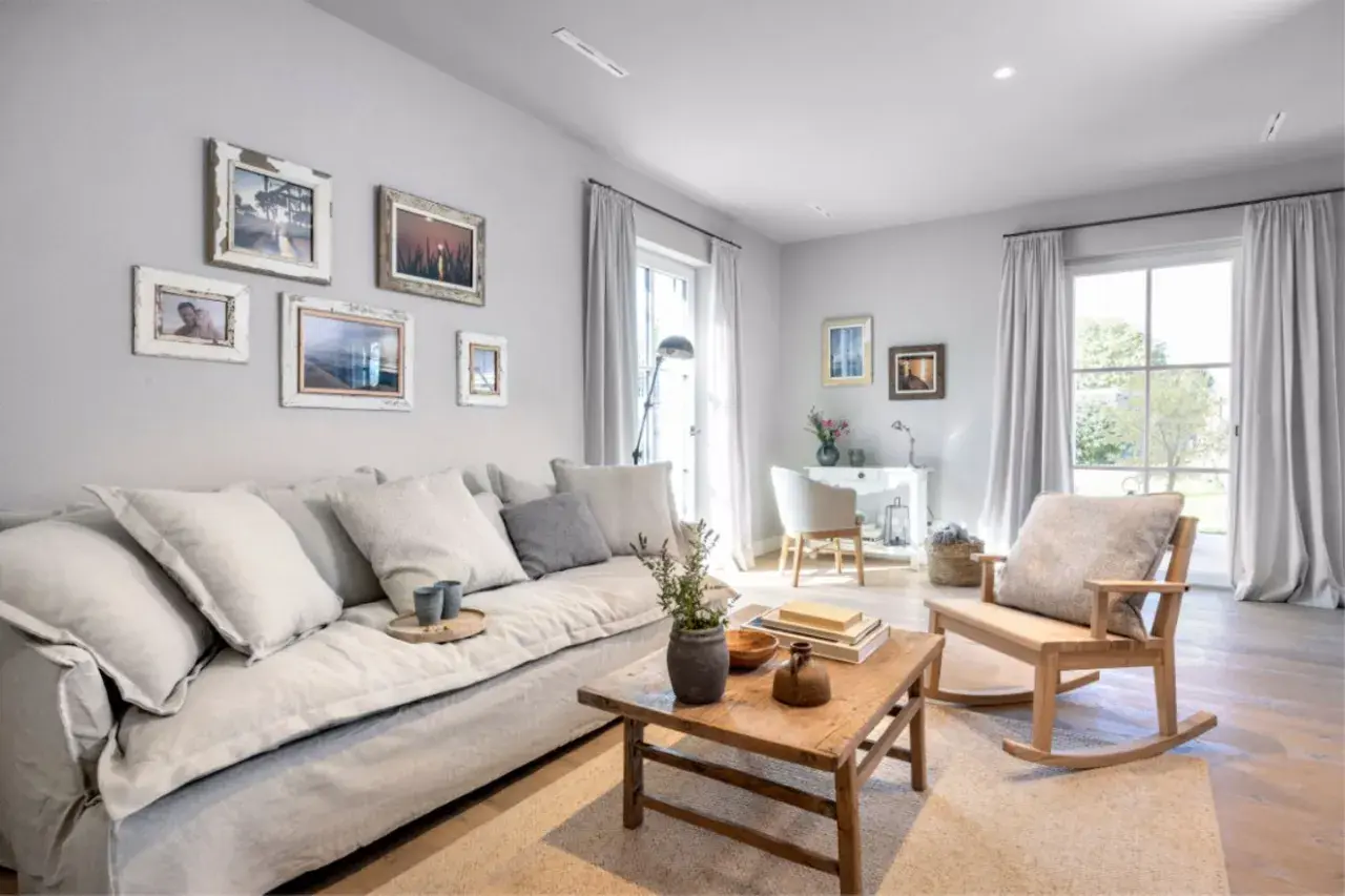 Gemütliches Wohnzimmer in millennial grey mit großem Sofa, Holztisch und Schaukelstuhl. Bilderrahmen zieren die Wand.