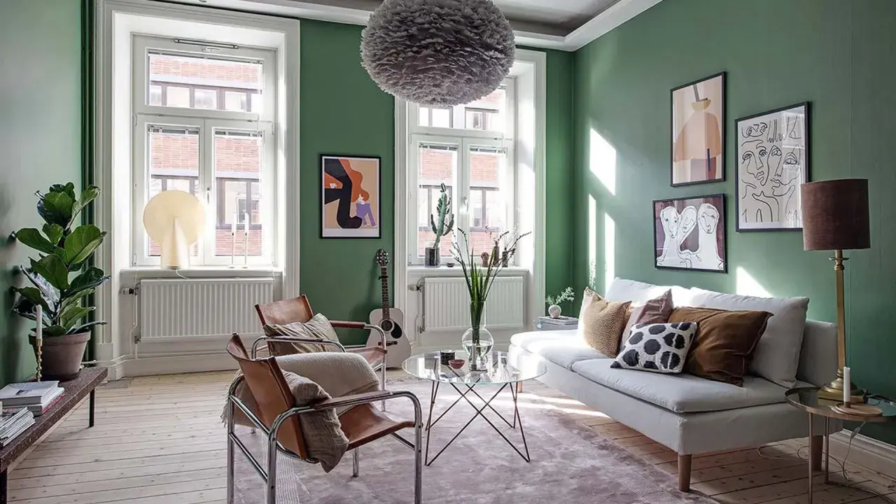 Salón verde con sofá blanco, sillones de cuero y arte abstracto. Ideas para **como ahorrar en calefacción** con estilo.