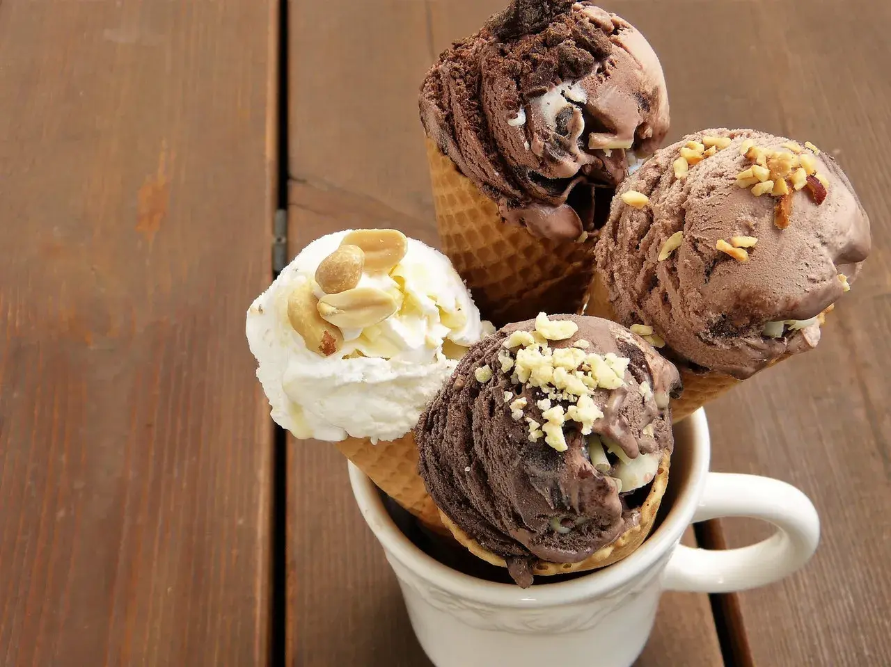 Cuatro helados en conos, dos de chocolate y uno blanco con cacahuates, perfectos como helados para diabéticos tipo 2.