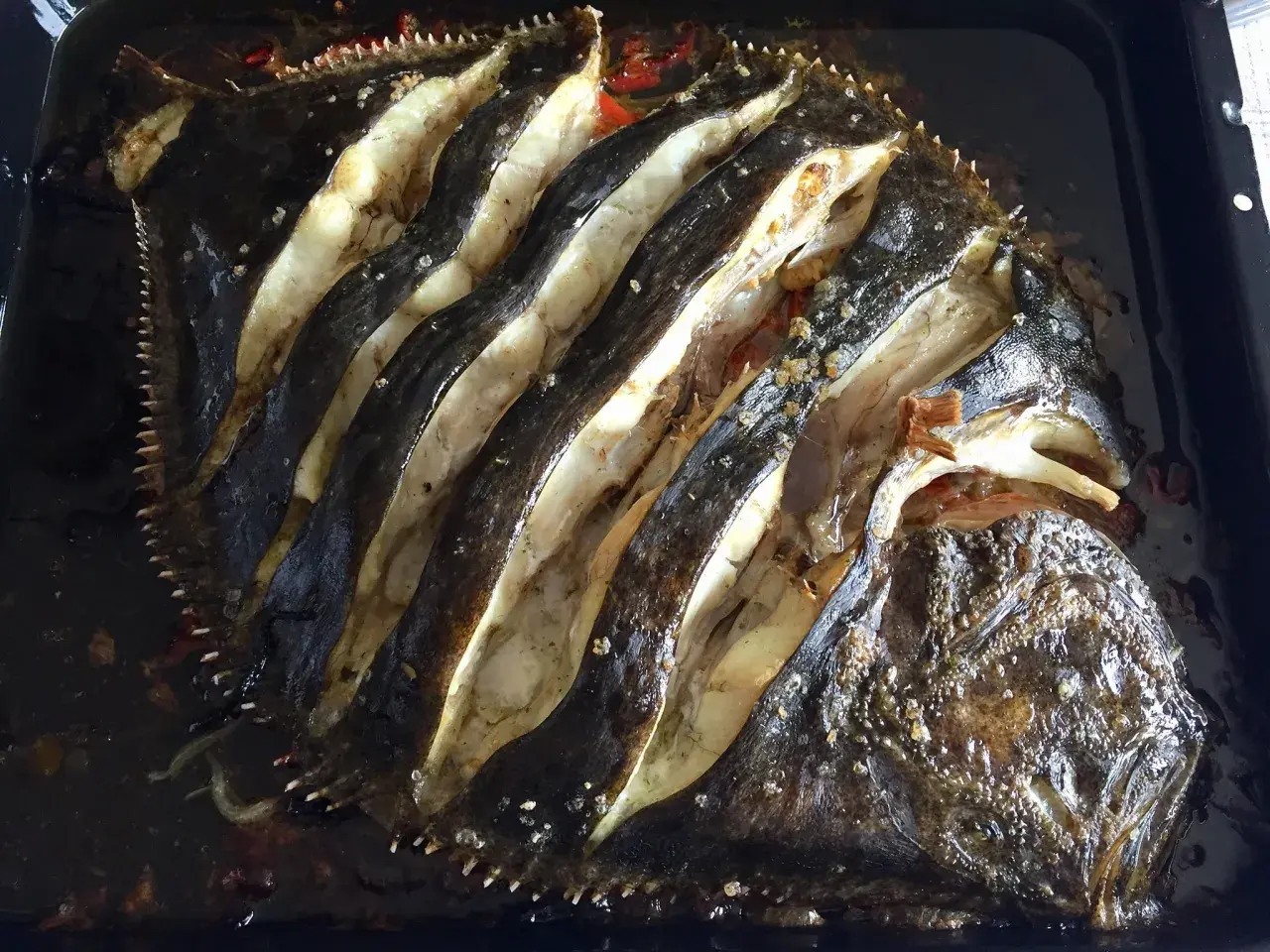 Rodaballo al horno, con cortes profundos que revelan su carne blanca y jugosa, listo para ser disfrutado.