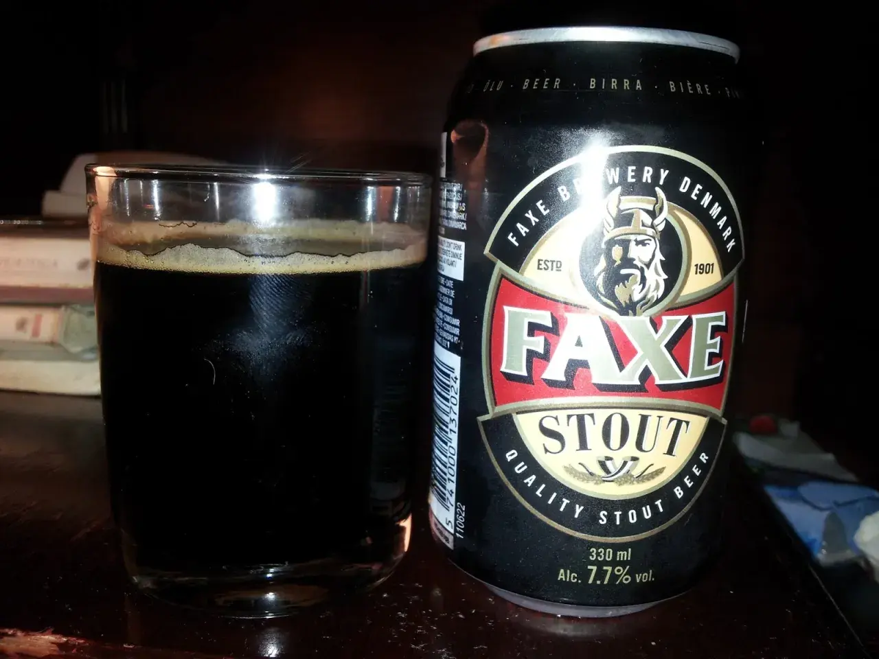 Szklanka ciemnego piwa obok puszki piwa Faxe Stout. Idealne na wieczór z dobrą książką.