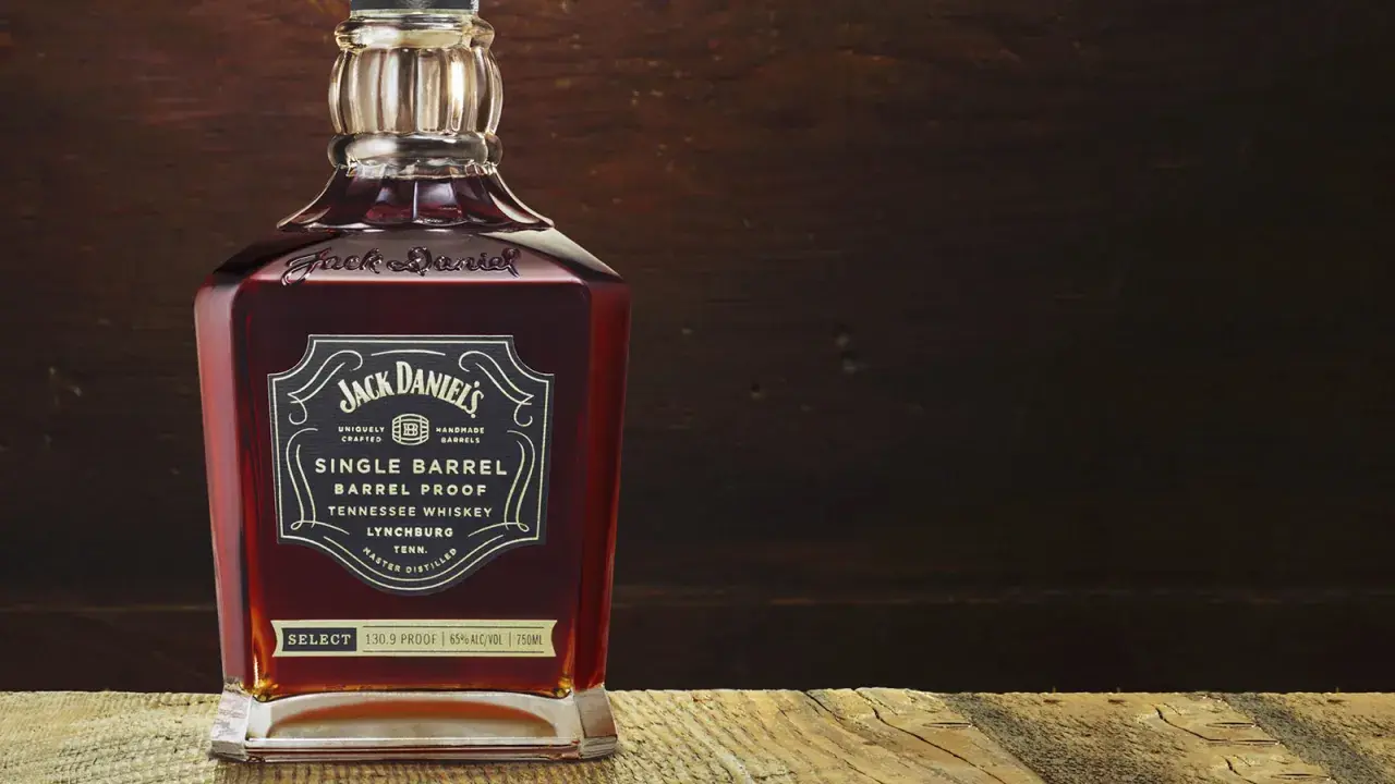 Butelka Jack Daniel's Single Barrel Tennessee Whiskey, z bogatym, bursztynowym kolorem, stoi na drewnianym blacie.