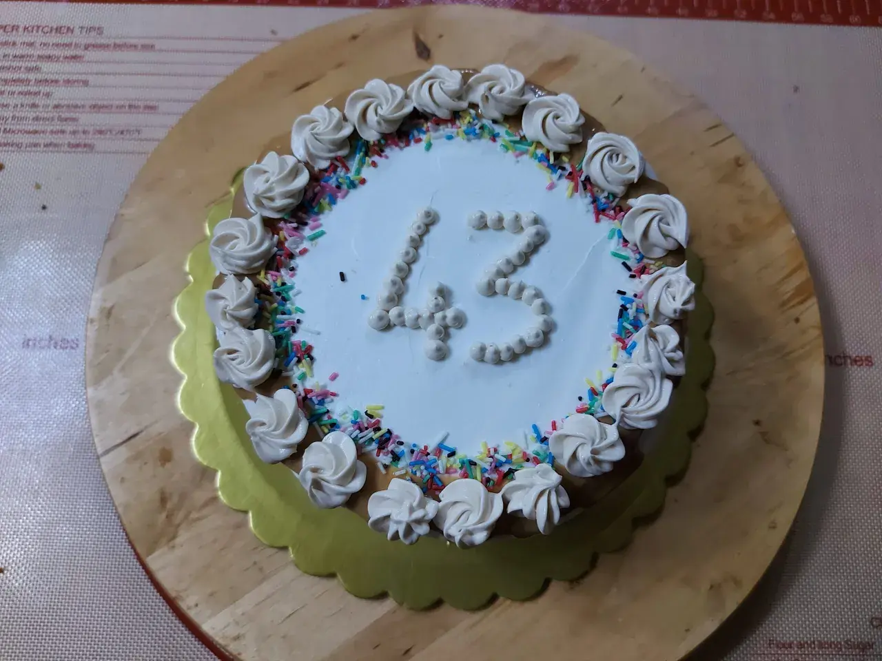 Torta di compleanno particolare con decorazioni a rosa e codette colorate, numero 43 in crema.