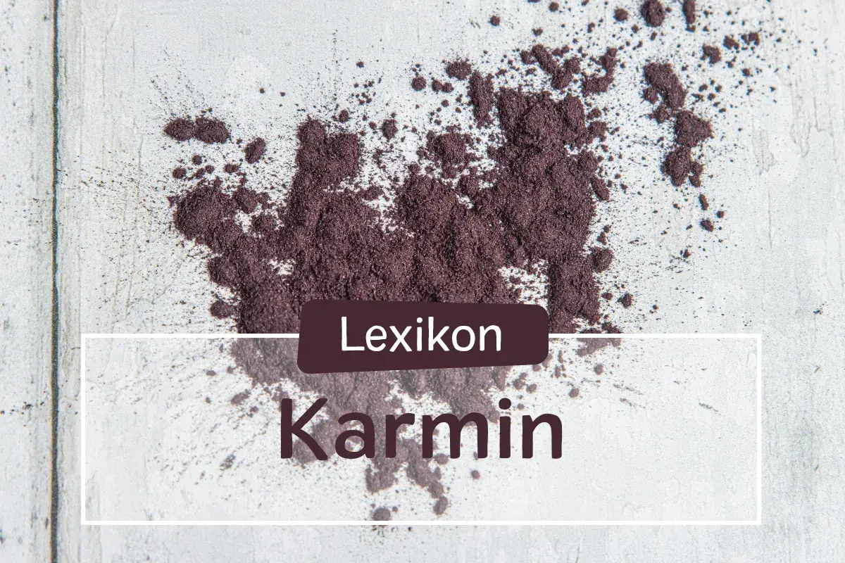 Ein Haufen echtes Karmin-Pulver, das auf einer hellen Oberfläche verstreut ist. Der Text "Lexikon Karmin" ist überlagert.