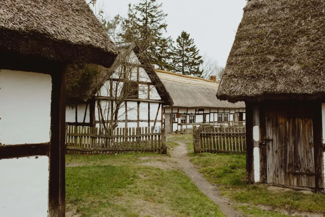 Skansen z chatami krytymi strzechą, drewnianymi płotkami i ścieżką. Idealne miejsce na odkrywanie kluki atrakcje.