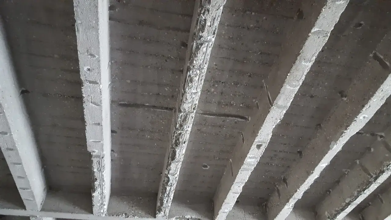 Unterseite einer stahlbeton rippendecke mit sichtbaren Rippen und Bewehrung.