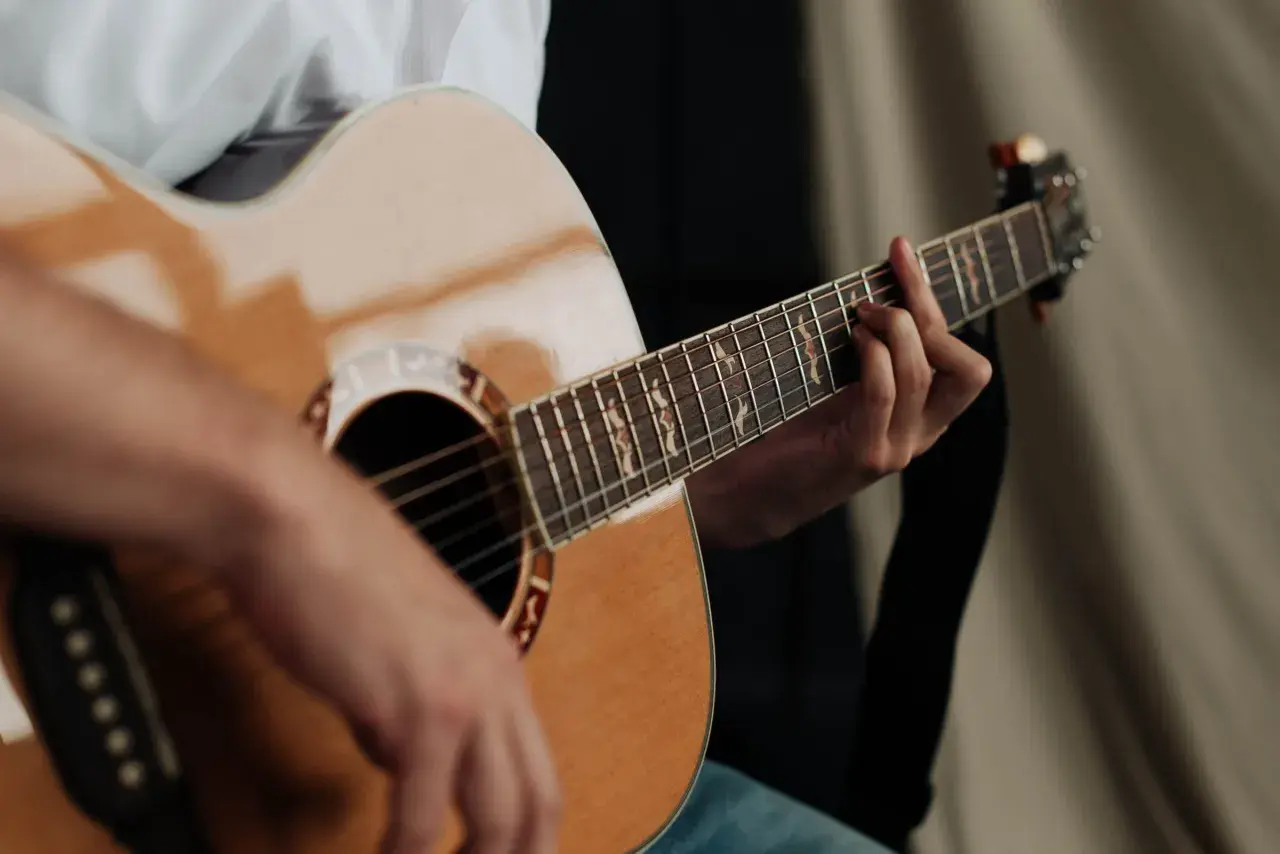 Dłoń grająca na gitarze akustycznej. Czy gra na gitarze jest trudna? Zależy od determinacji i praktyki!