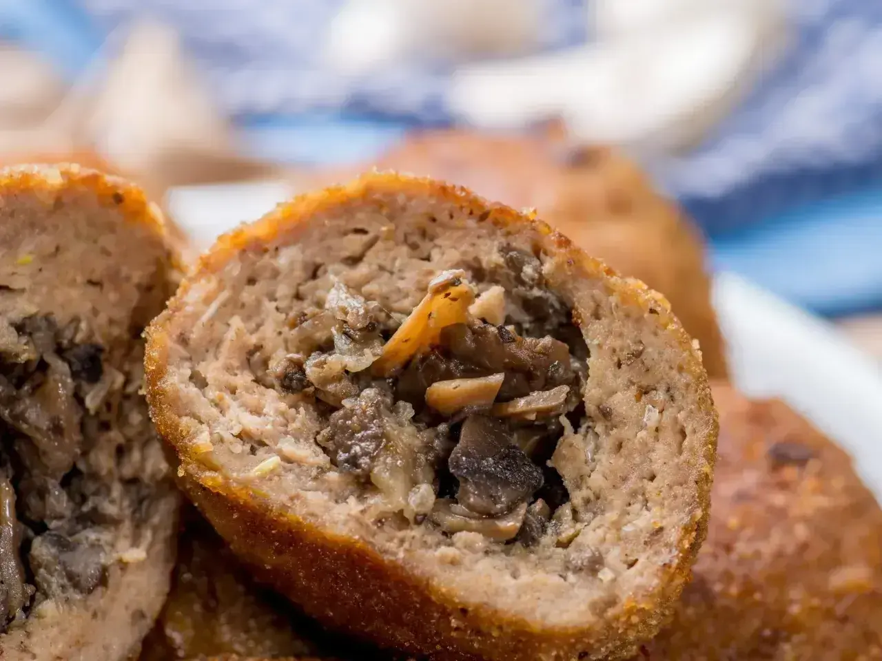 Kotlety mielone z pieczarkami, przekrojone na pół, ukazujące soczyste, aromatyczne wnętrze.