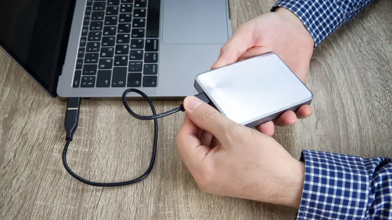 Hände verbinden eine externe Festplatte mit einem Laptop. Plötzlich kein Zugriff auf externe Festplatte.