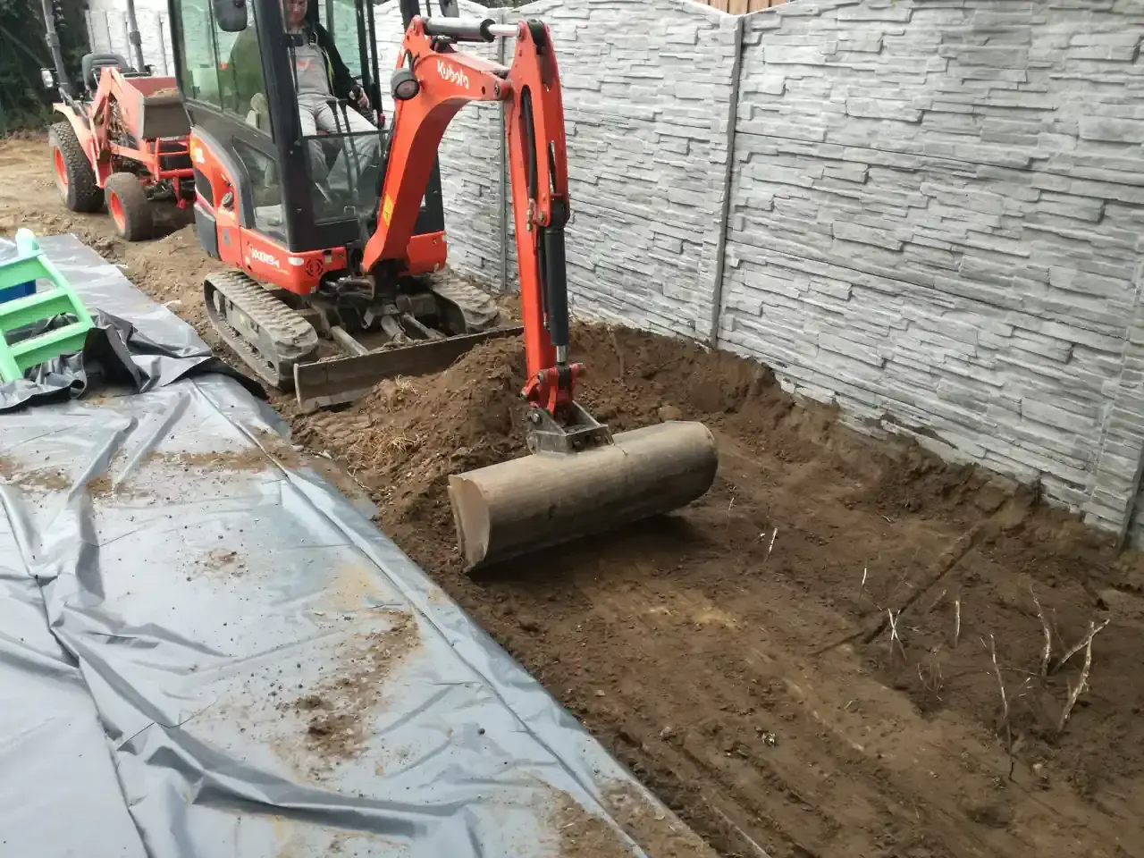 Koparka pracuje nad przygotowaniem terenu pod budowę, usuwając ziemię i przygotowując podłoże.