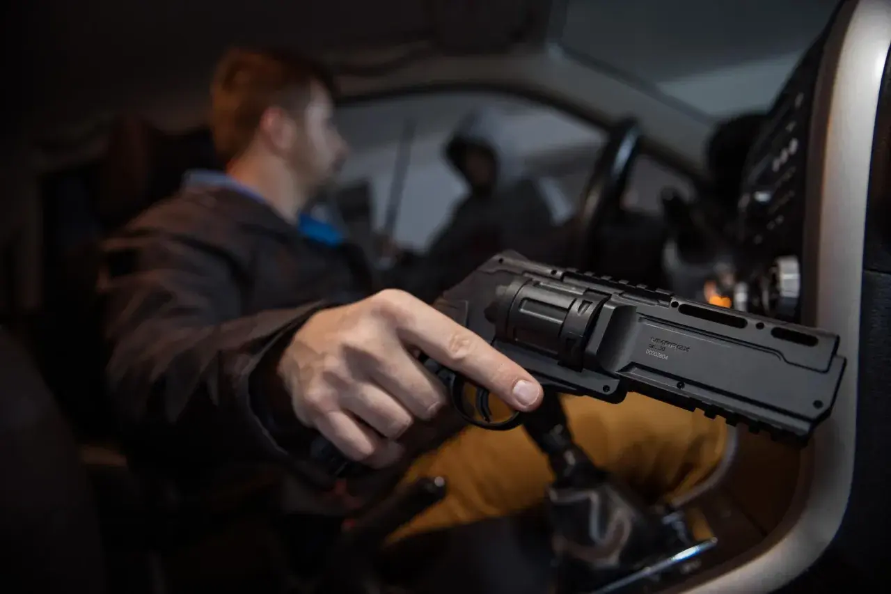 Mężczyzna w samochodzie trzyma pistolet na kule gumowe. Czy pistolet na kule gumowe jest legalny? To pytanie nurtuje wielu.