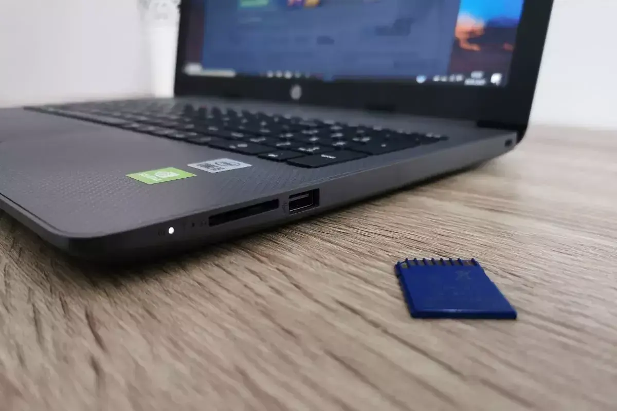 Obok laptopa leży niebieska karta pamięci. Dysk jest zabezpieczony przed zapisem, co uniemożliwia modyfikację danych.