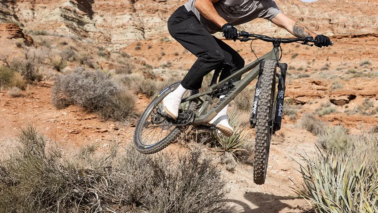 Mountainbiker auf einem Canyon Nerve AL 8.0 im Sprung in einer staubigen Wüstenlandschaft.
