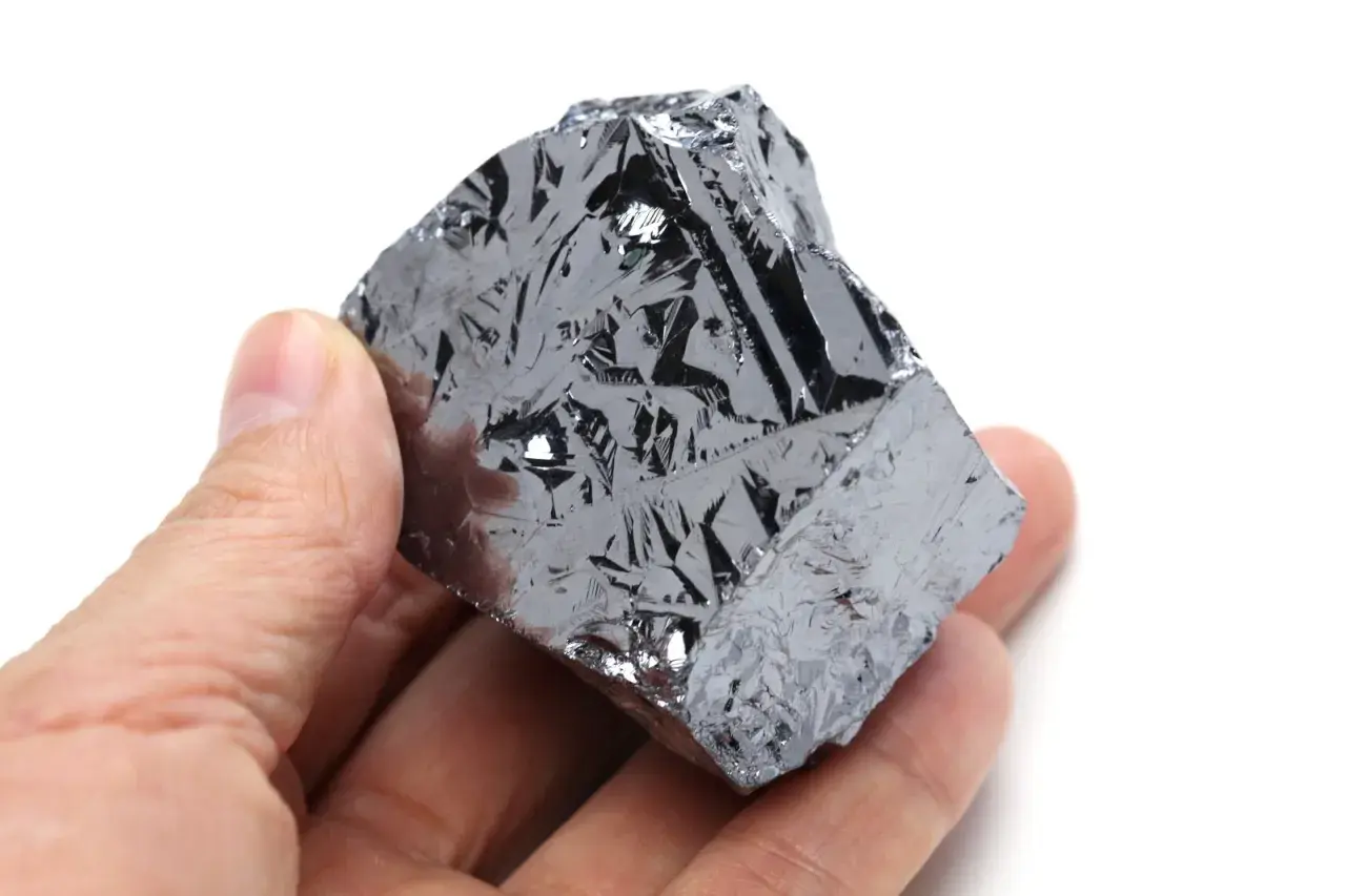 Ein Mensch hält ein Stück Silizium, dessen Oberfläche wie eine glänzende, metallische Haut mit komplexen Mustern aussieht.