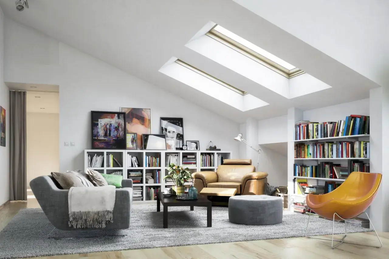 Gemütliche dachgeschosswohnung einrichten mit bequemen Sesseln, Bücherregalen und viel Licht durch Dachfenster.