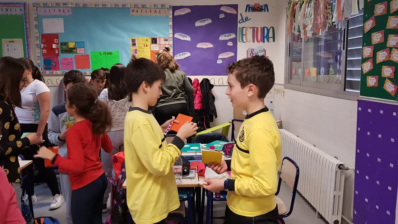 Niños participando en dinámicas de grupo en un aula, interactuando y compartiendo materiales.