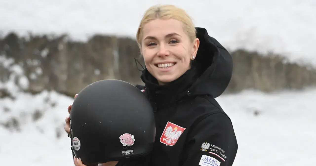 Uśmiechnięta Klaudia Adamek trzyma kask. Na jej kurtce widnieje godło Polski.